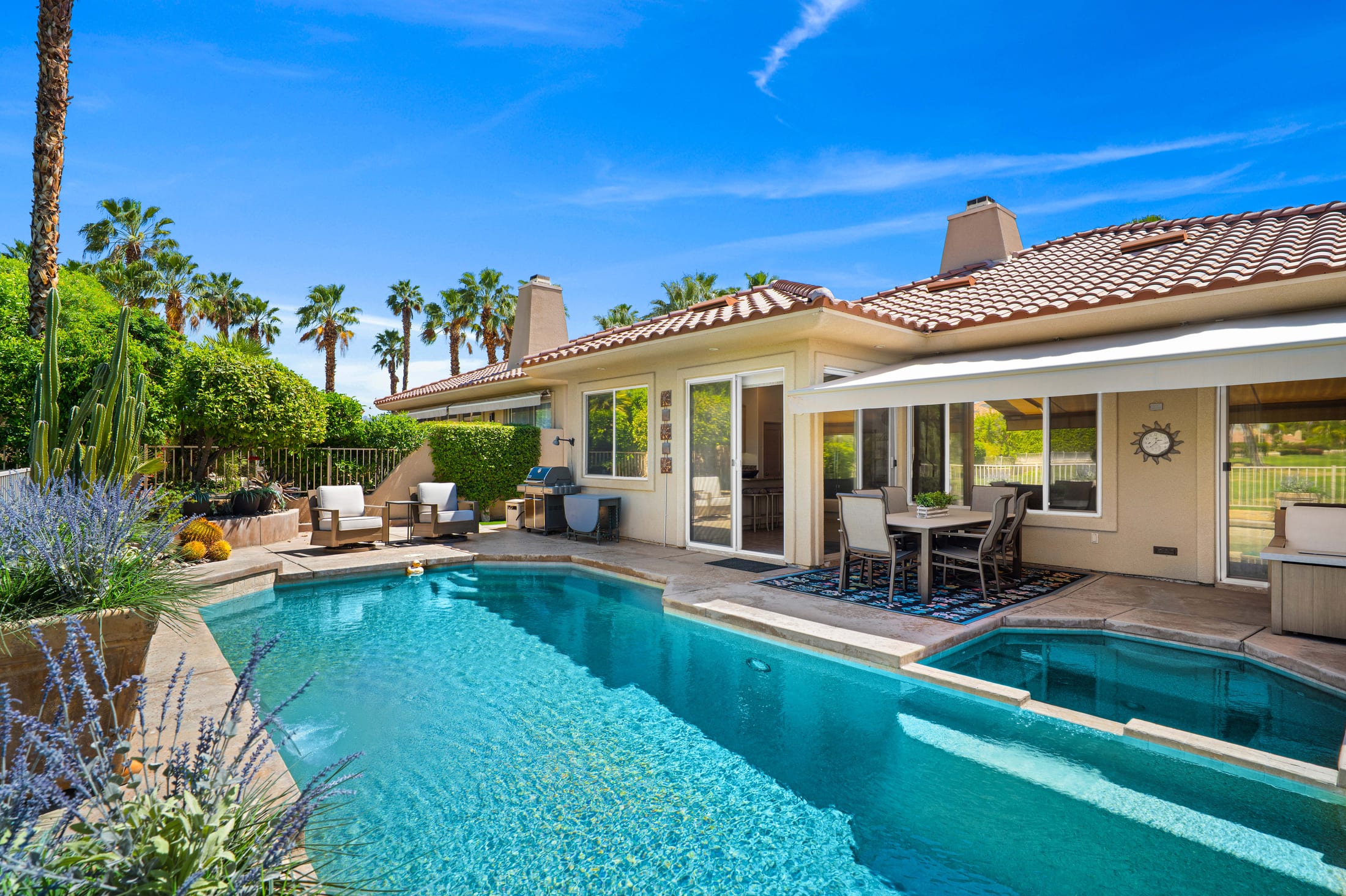 Backyard pool and covered patio photographed at midday under a hard blue sky
